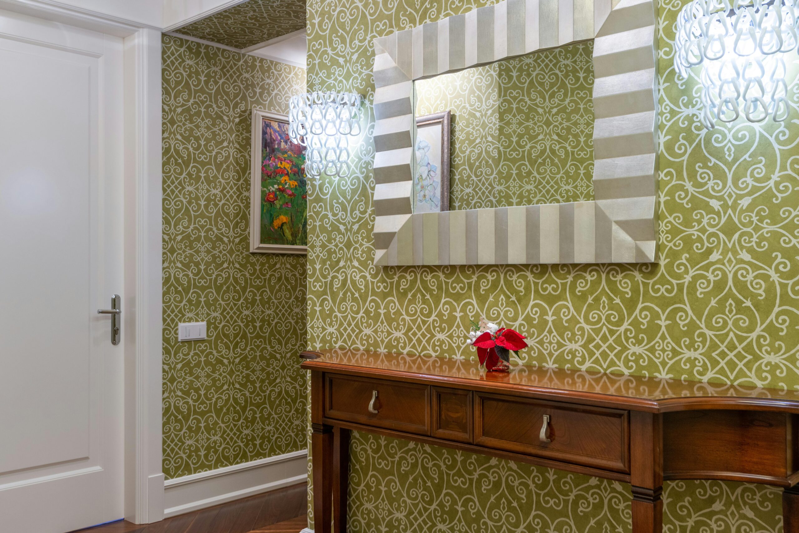 Sophisticated hallway featuring ornate wallpaper, a wooden console, and a striking decorative mirror.